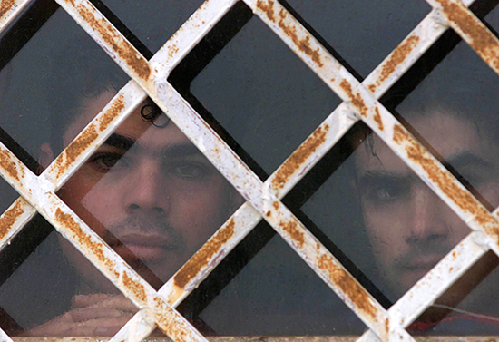 TWO IRAQI REFUGEES LOOK THROUGH BARRED WINDOW IN LUBIMETZ